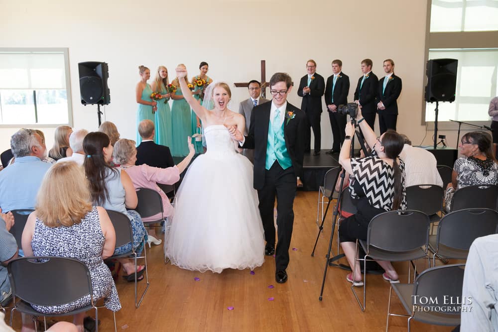 Bride and groom come down the aisle at the conclusion of their wedding ceremony as the bride punches the air in celebration