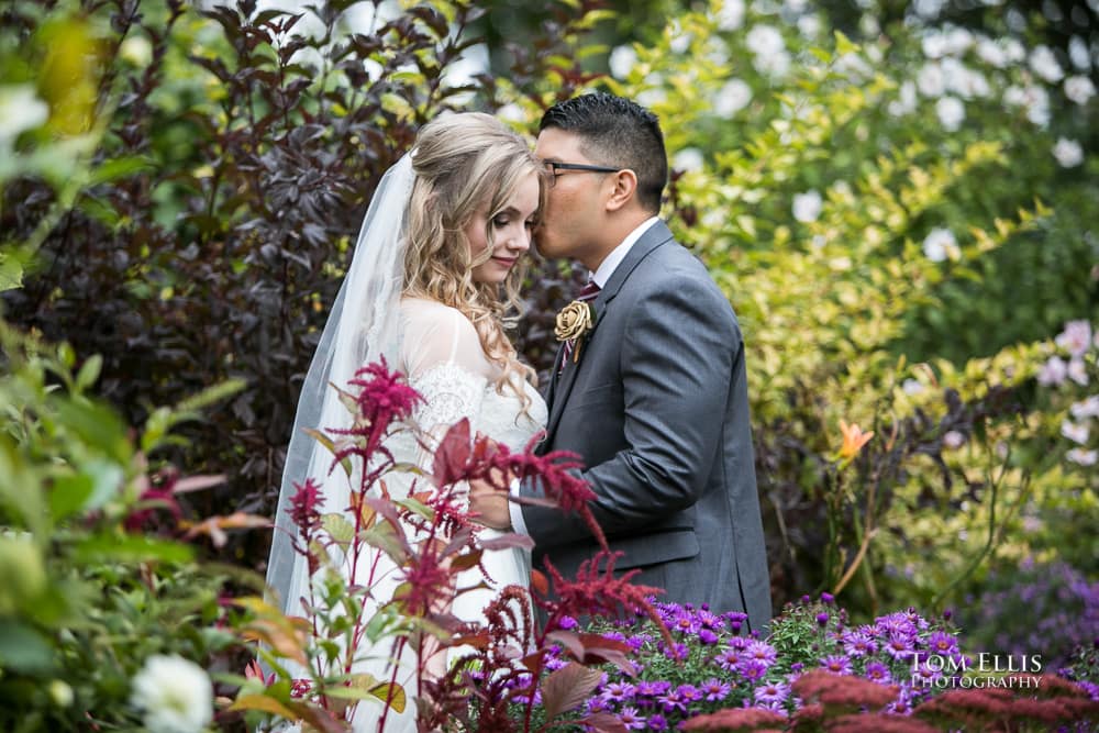 Bride and groom hug in a beautiful flower garden during their pre-ceremony photo session, by Tom Ellis Photography, top rated wedding photographer in Seattle